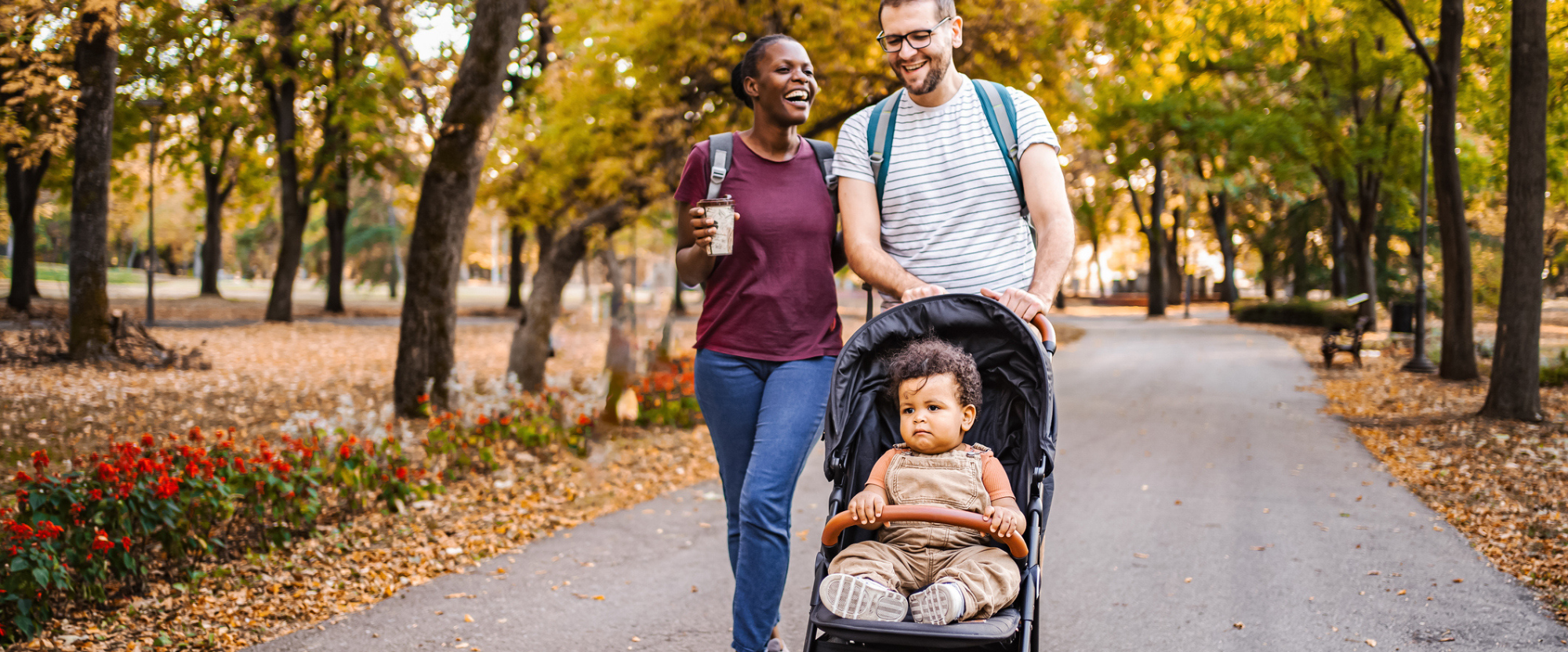 Best Baby Strollers 2024 featuring a mixed race couple walks with their son in stroller through the park
