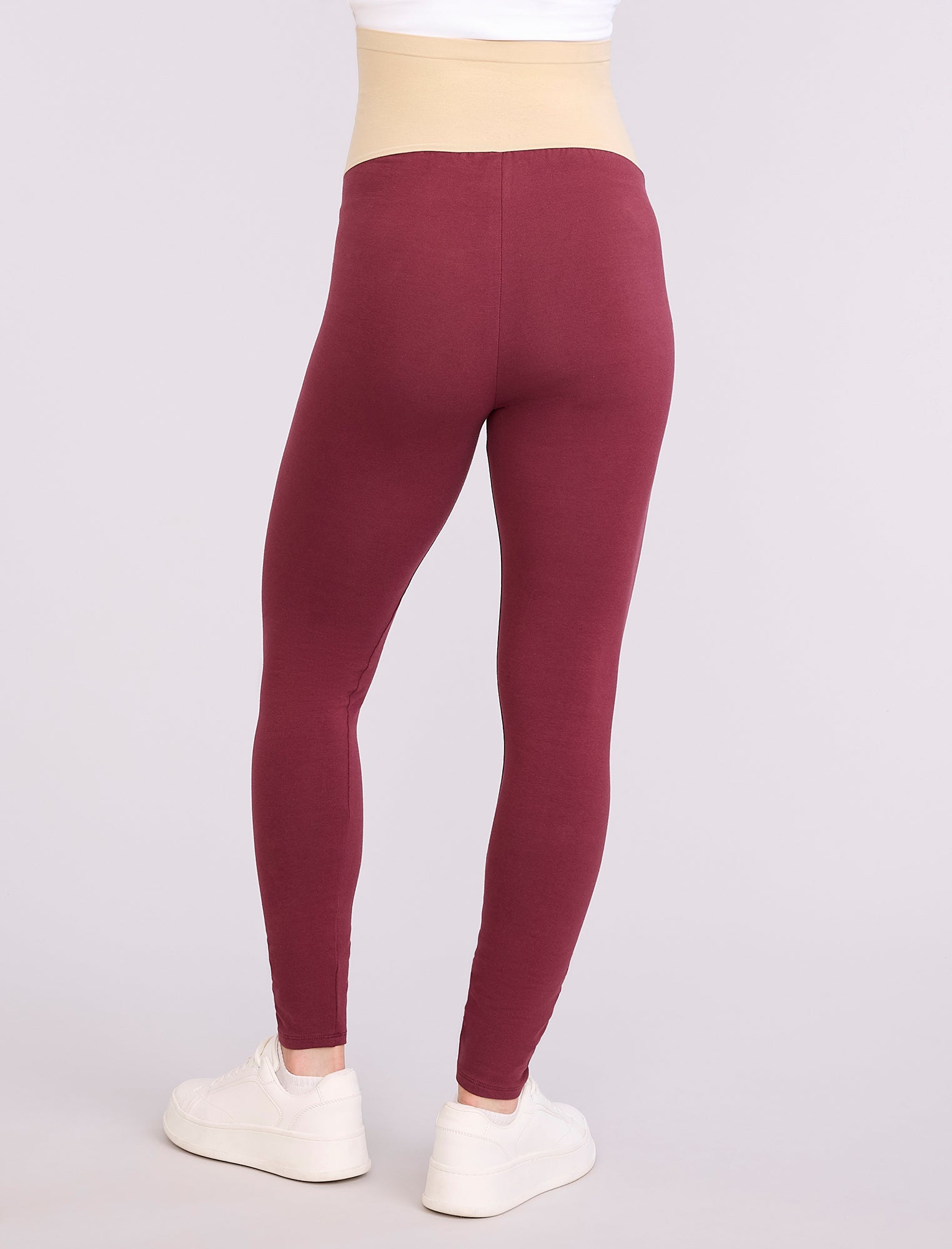 Maroon leggings worn by a pregnant woman on a white background