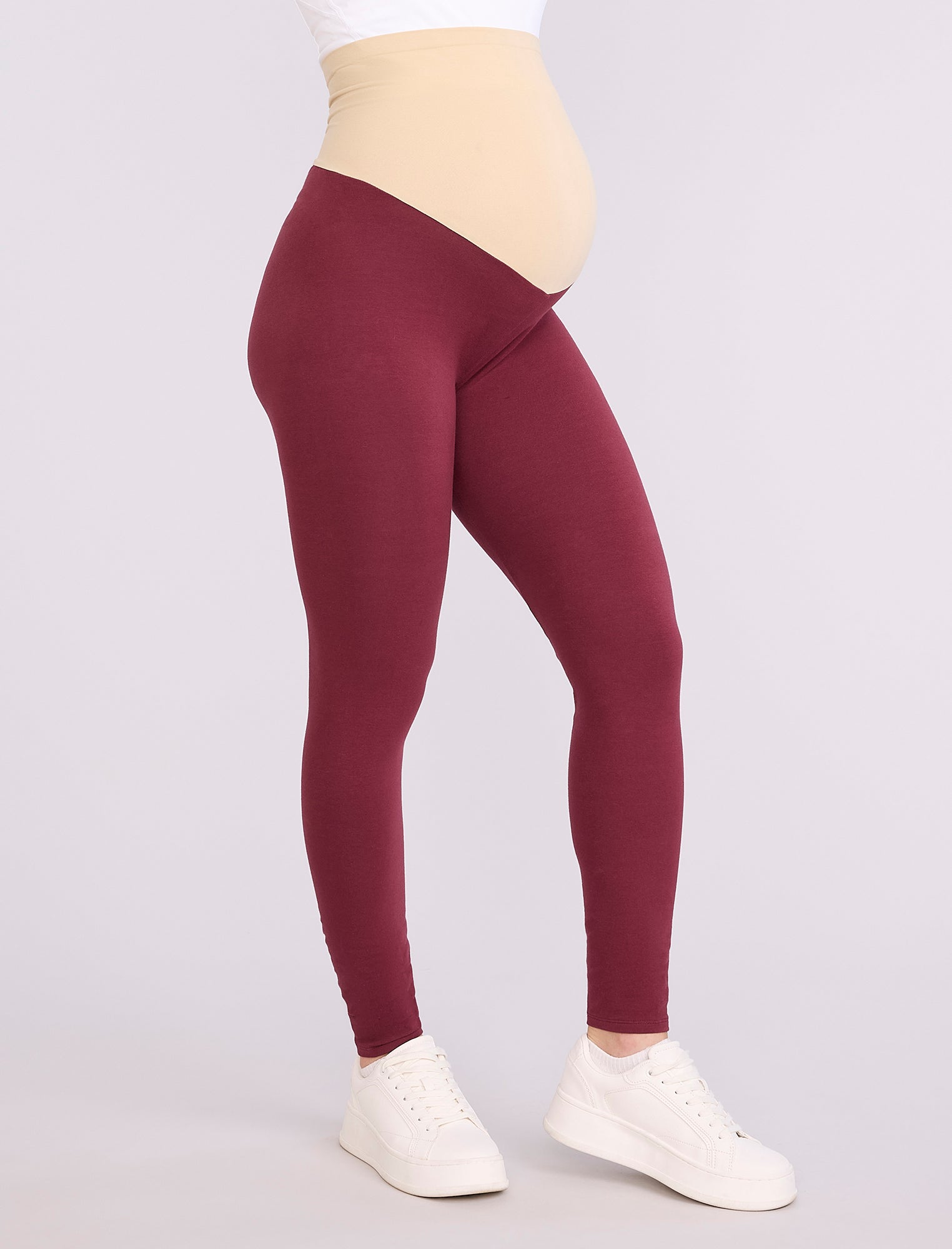 Maroon leggings worn by a pregnant woman on a white background