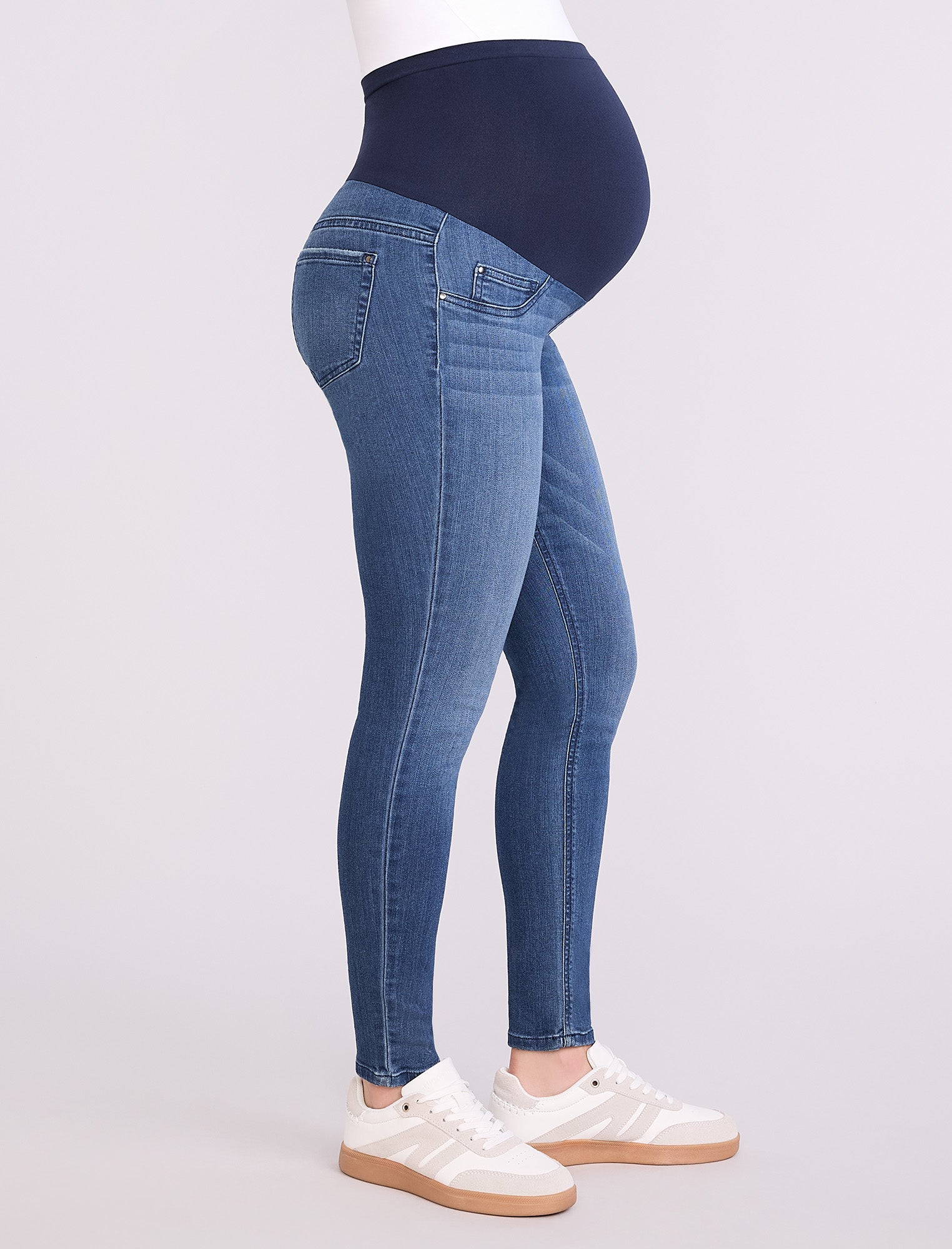 Blue maternity jeans worn by a person on a white background