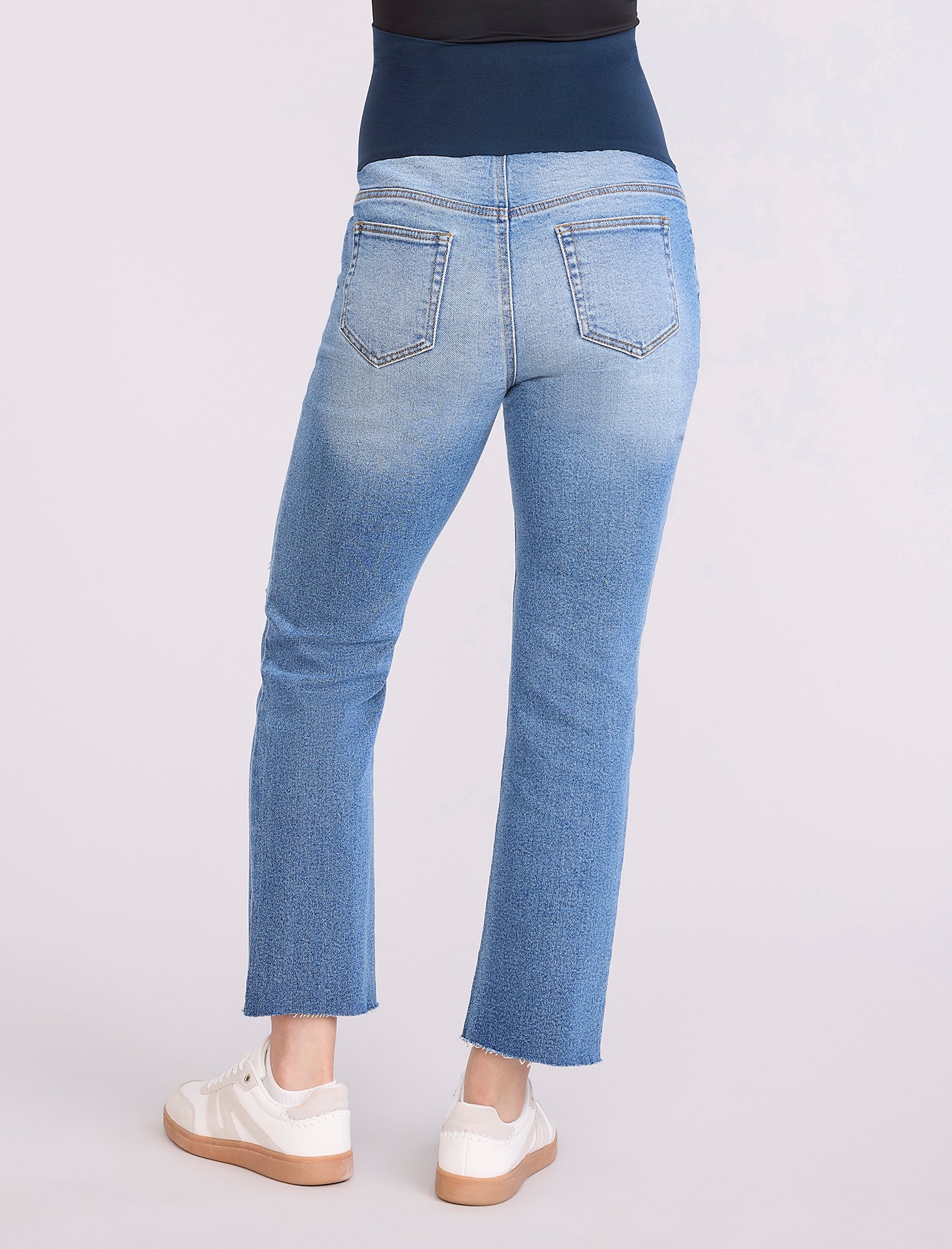 Blue jeans worn by a pregnant woman on a white background