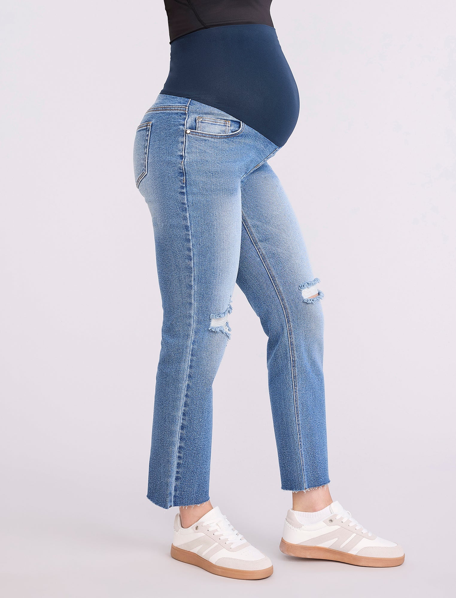 Blue jeans worn by a pregnant woman on a white background