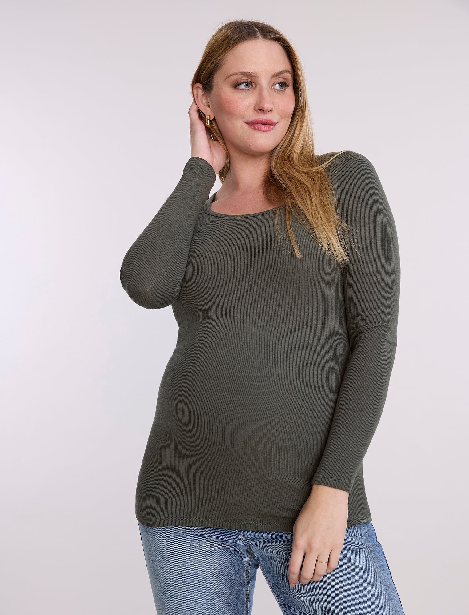Pregnant woman wearing a green long-sleeve top against a white background