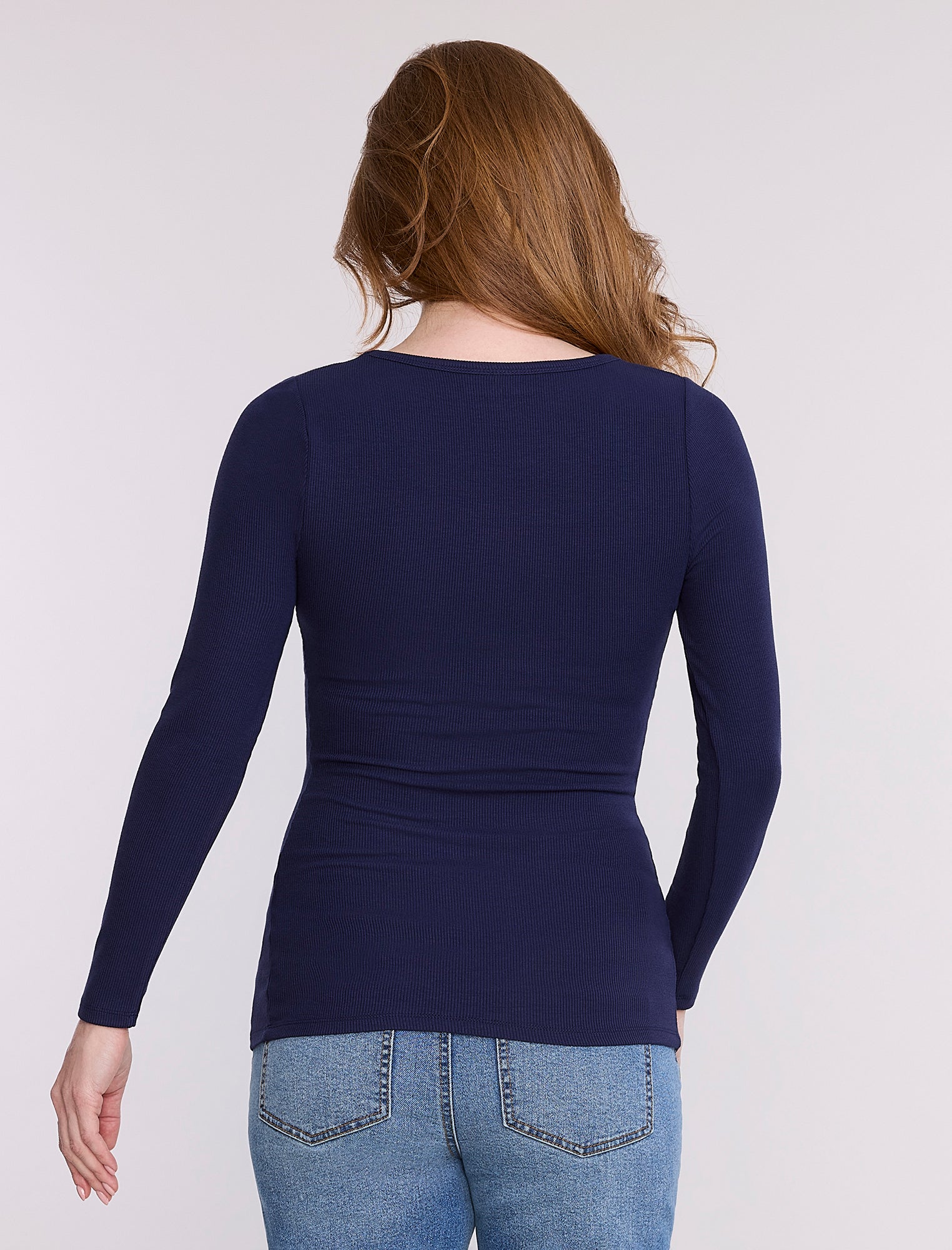 Pregnant woman wearing a dark blue long-sleeve top against a white background