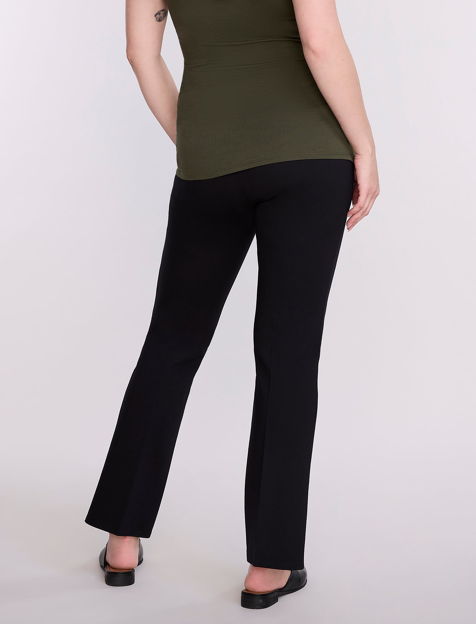 Pregnant woman wearing a green top and black pants on a white background