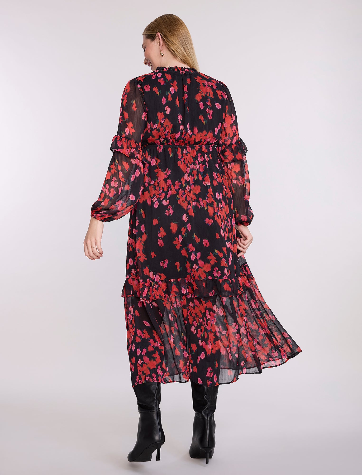 Pregnant woman wearing a red and black floral dress on a white background