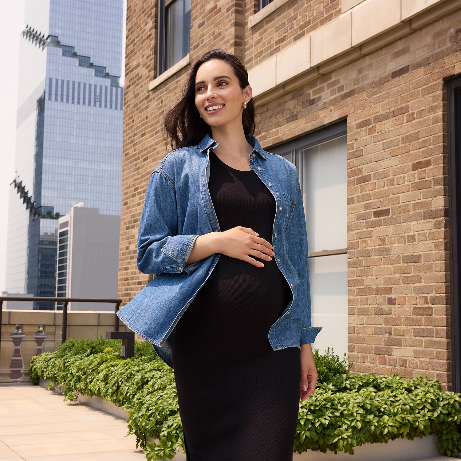 Pregnant woman standing outdoors with a cityscape background