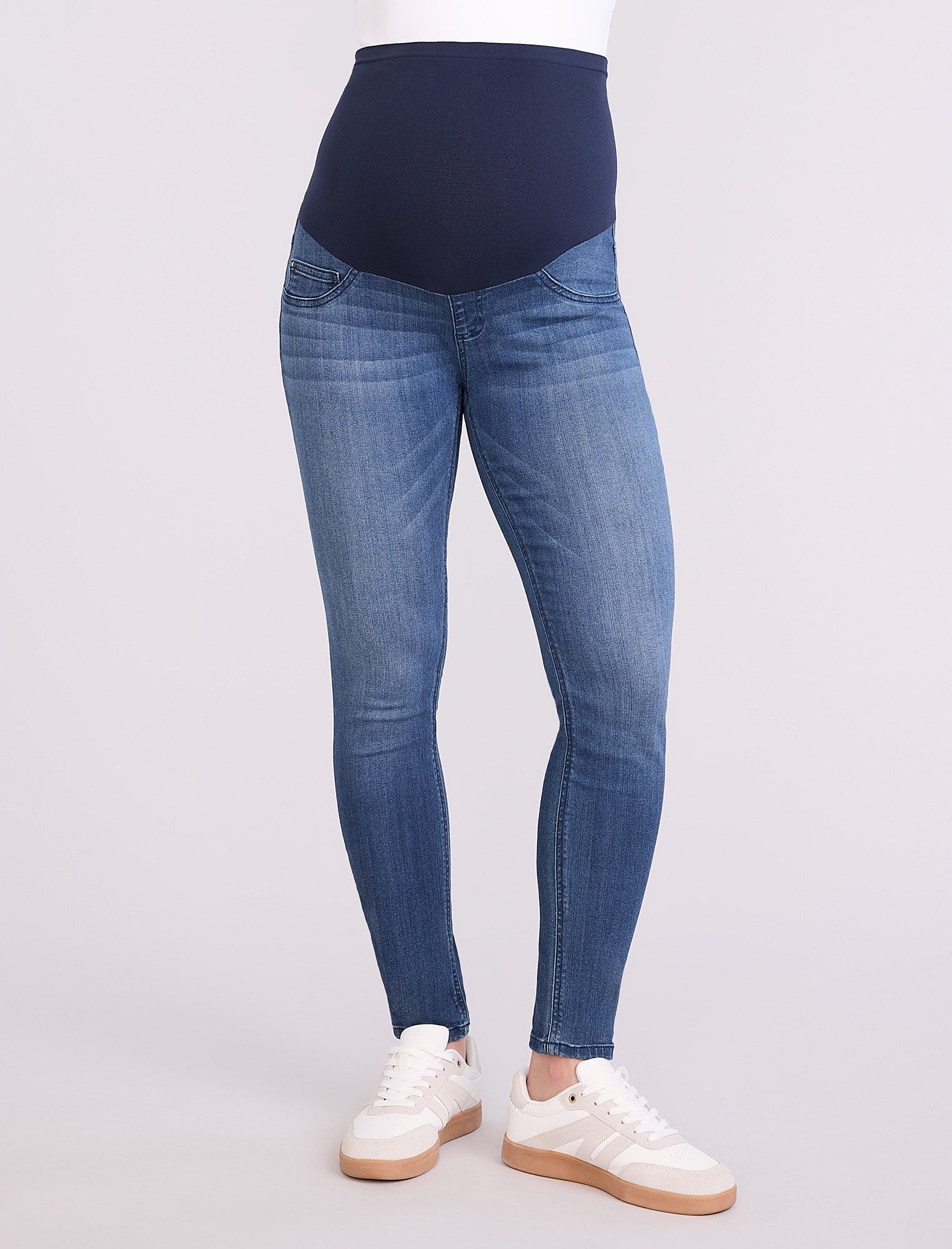 Blue maternity jeans worn by a person on a white background