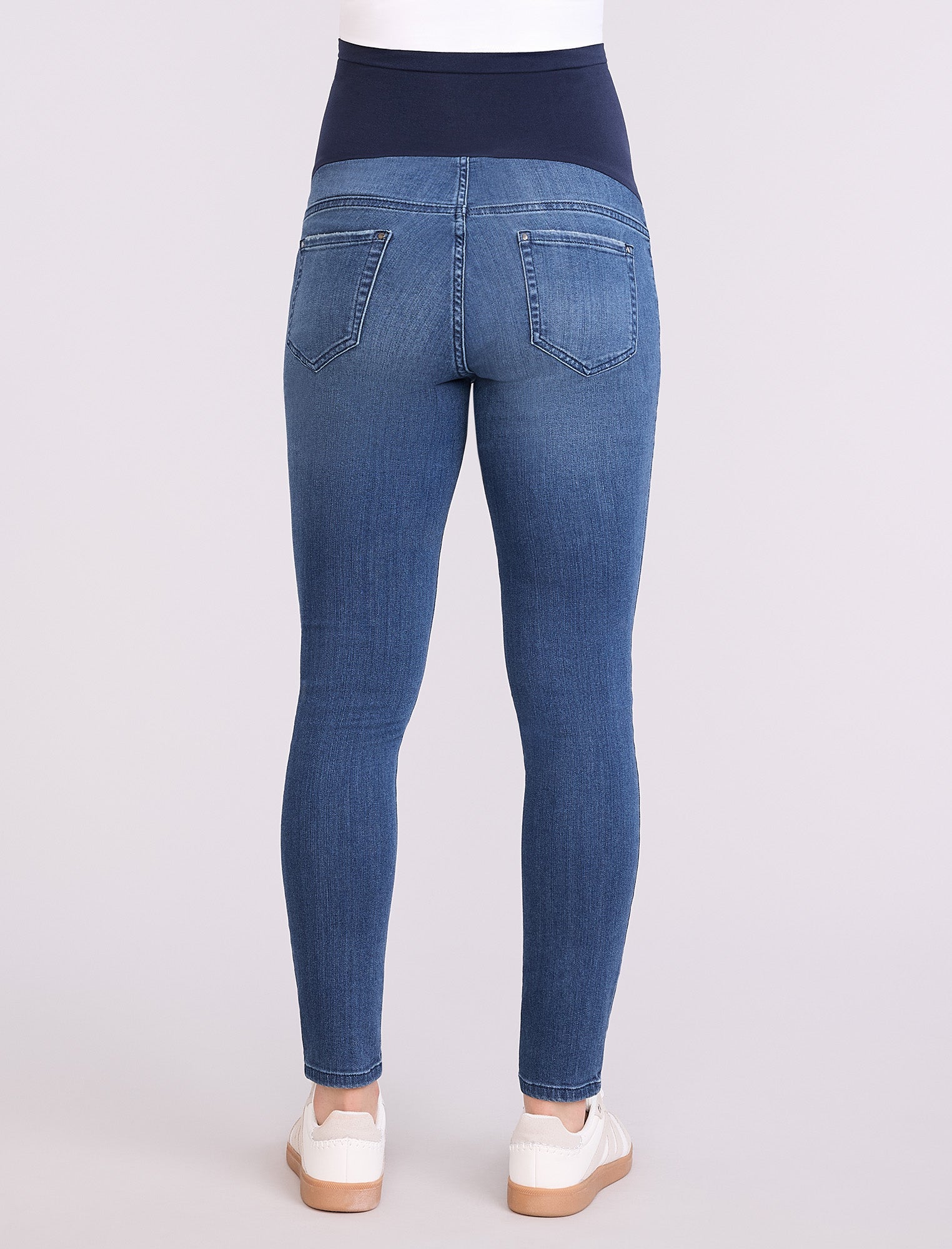 Blue maternity jeans worn by a person on a white background