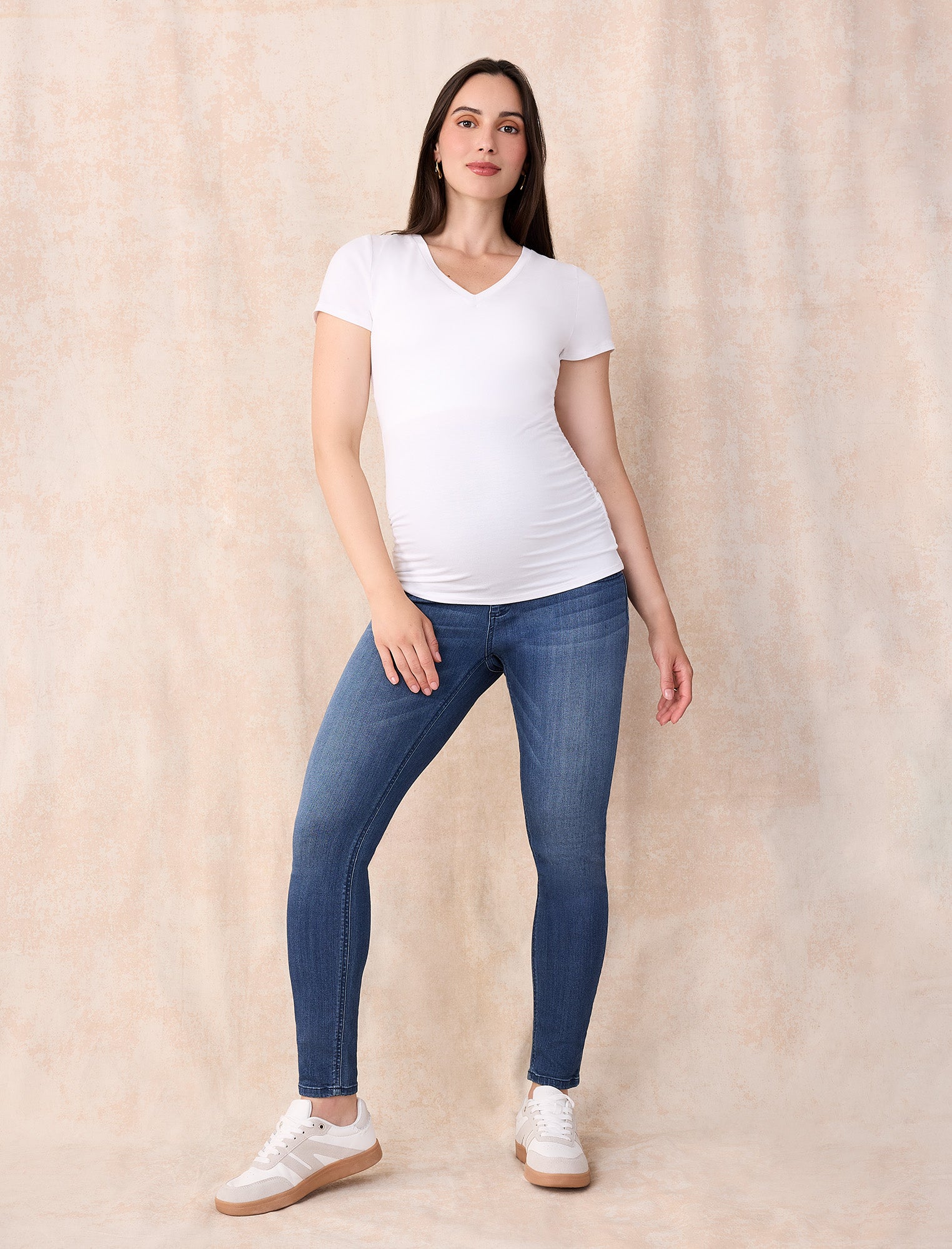 Blue maternity jeans and white t-shirt worn by a person on a white background