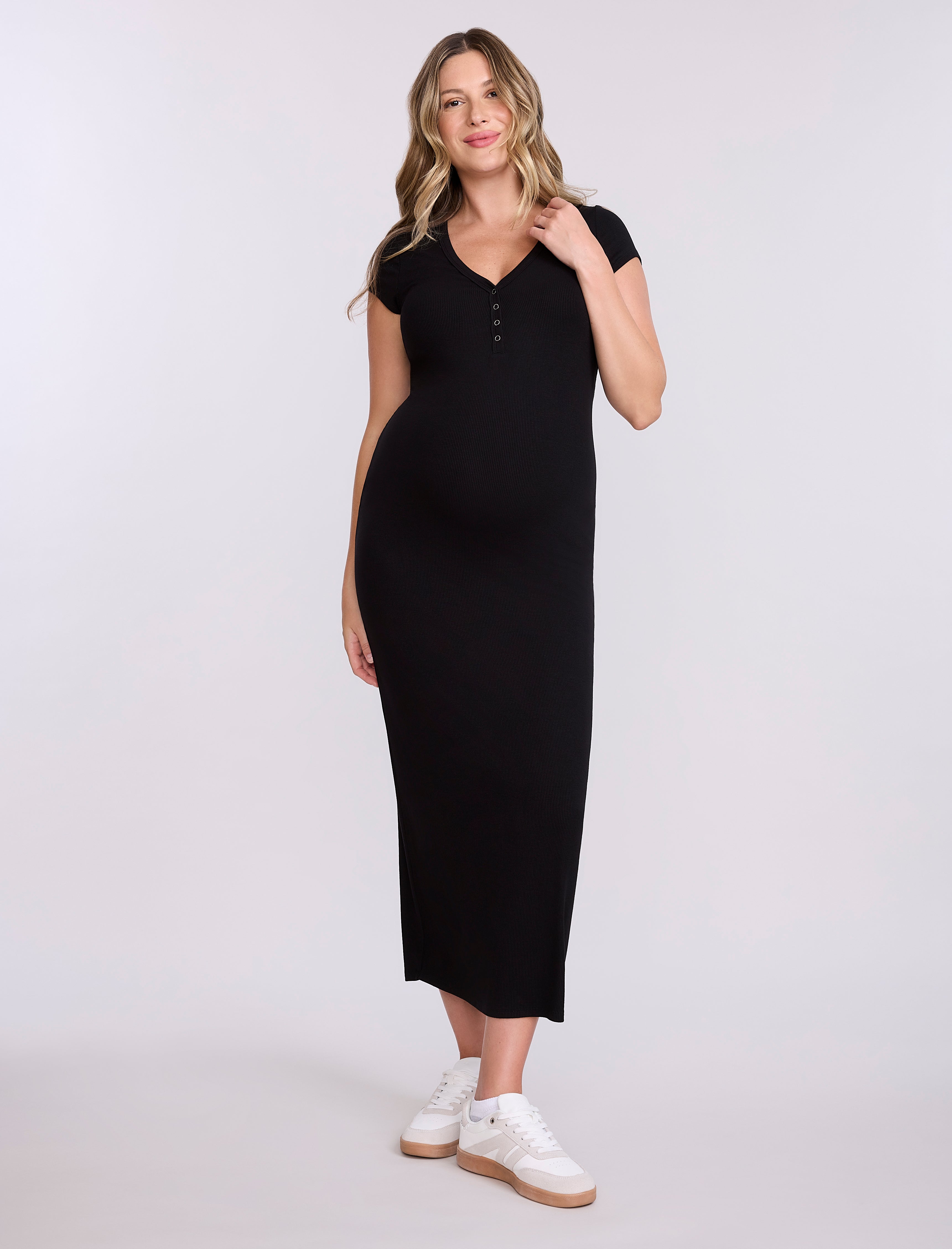 Woman wearing a black dress with white sneakers on a white background