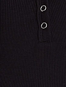 Close-up of a black ribbed sweater with silver buttons on a dark background