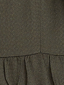 Pregnant woman wearing an olive green long-sleeve top against a plain background