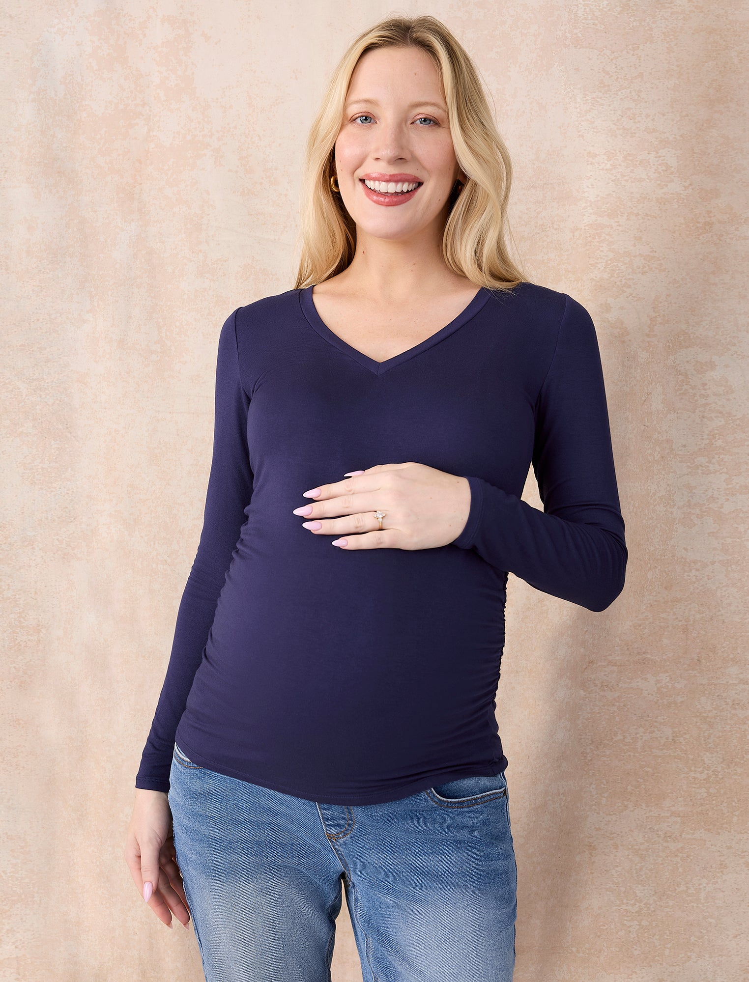 Pregnant woman wearing a dark blue long-sleeve top against a plain background