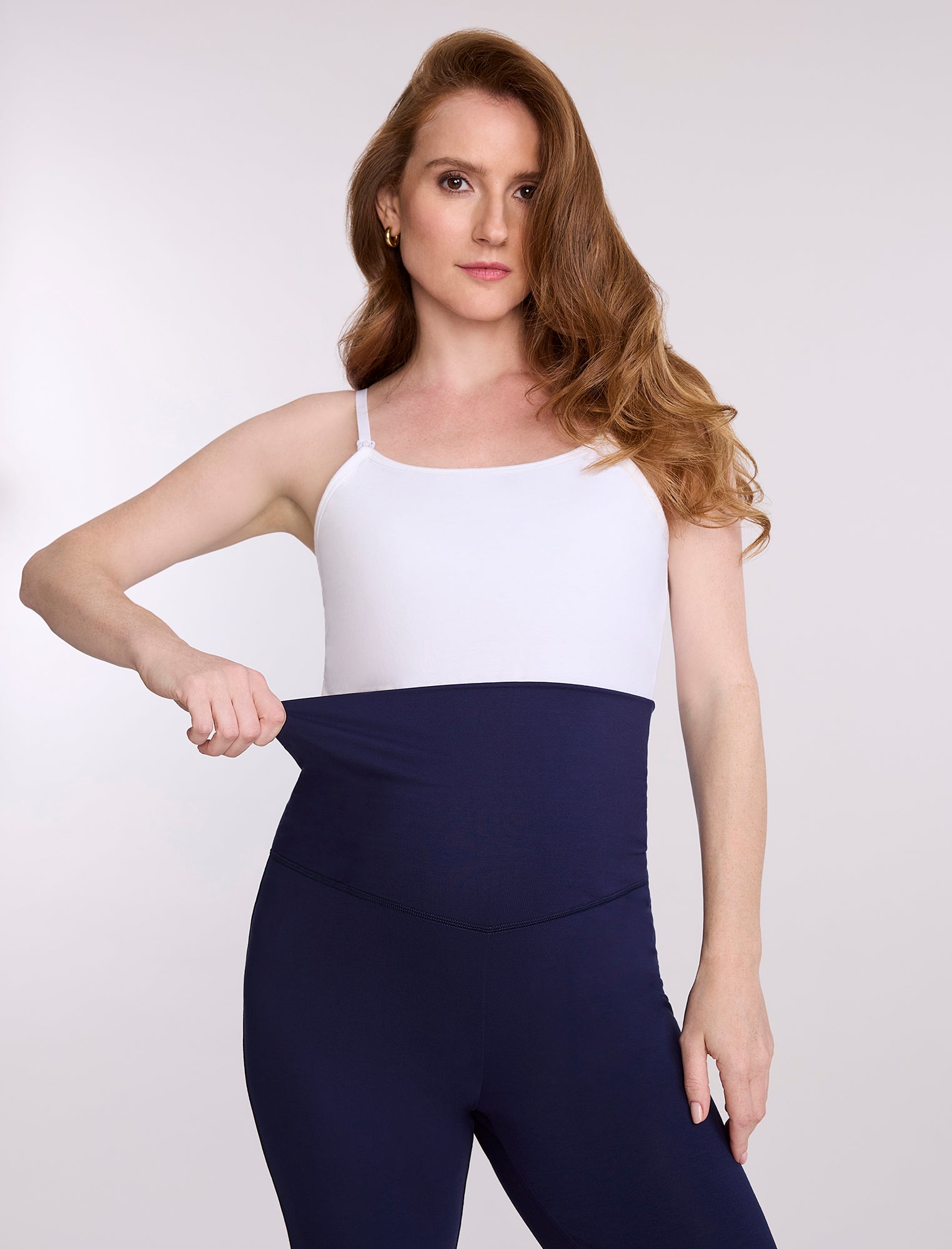 Navy blue maternity pants worn by a pregnant woman on a white background