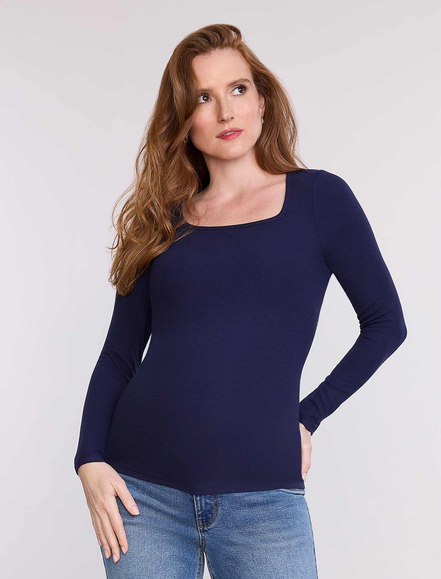 Pregnant woman wearing a dark blue long-sleeve top against a white background