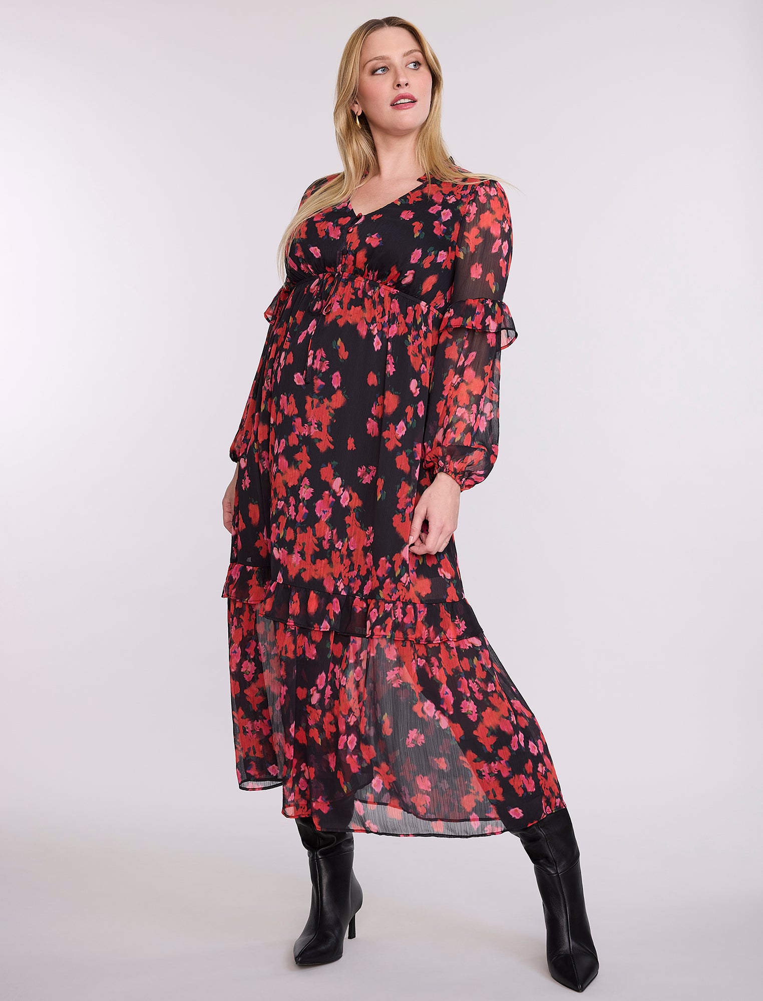 Pregnant woman wearing a red and black floral dress on a white background