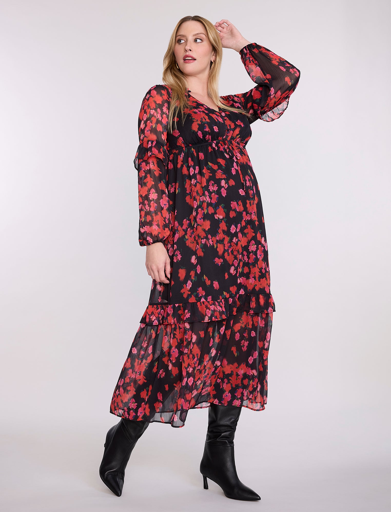 Pregnant woman wearing a red and black floral dress on a white background