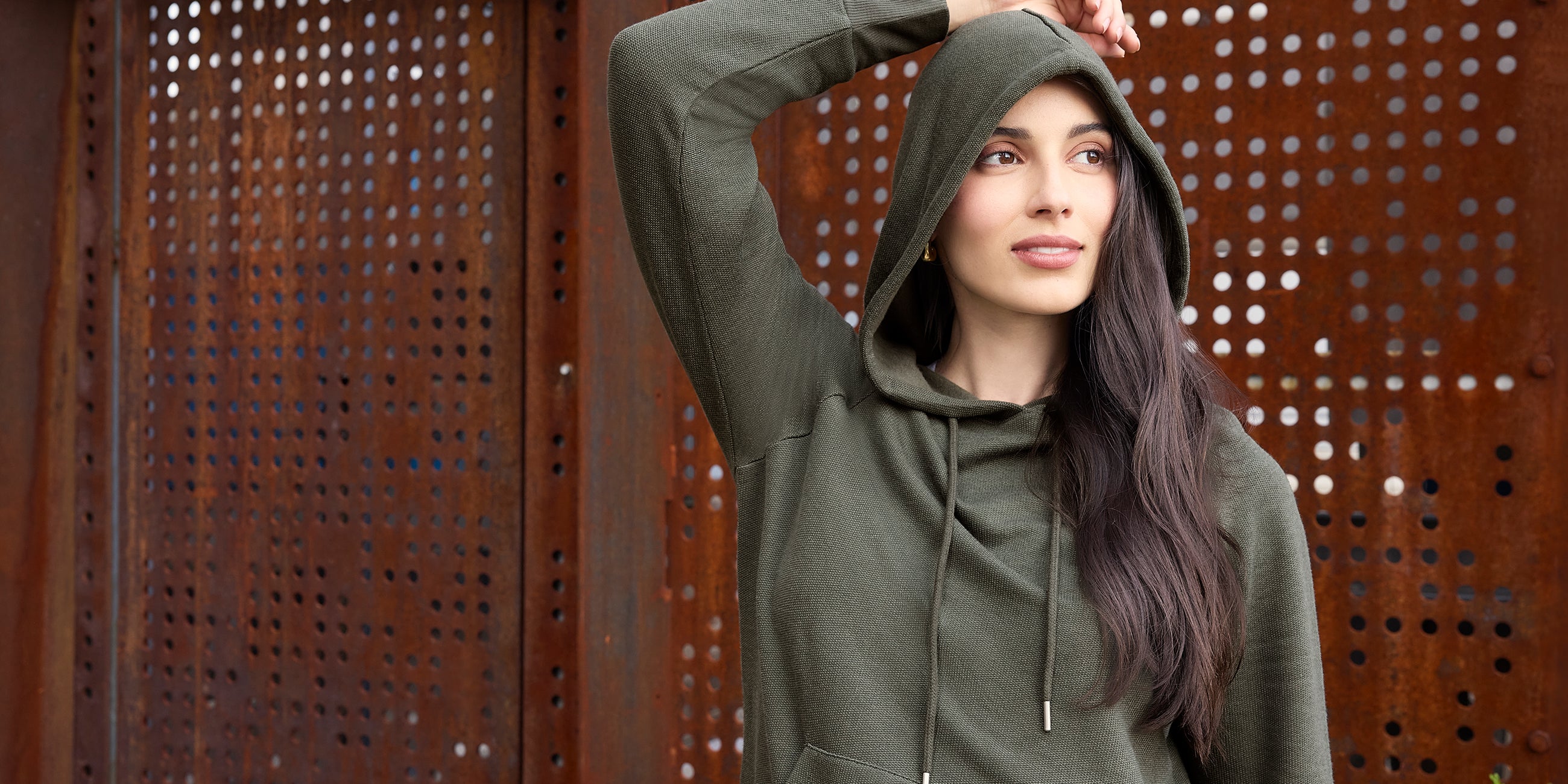 Woman wearing a green hoodie against a textured brown background