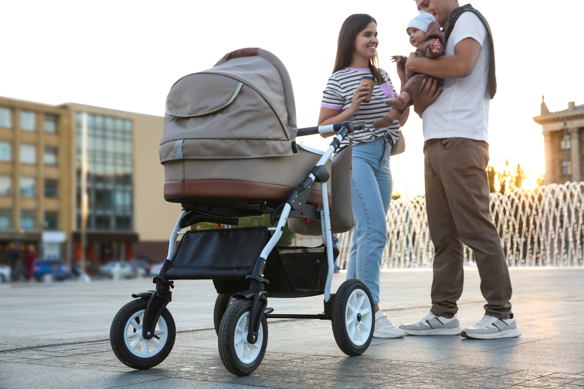 Woman and man standing outside by stroller holding a baby 