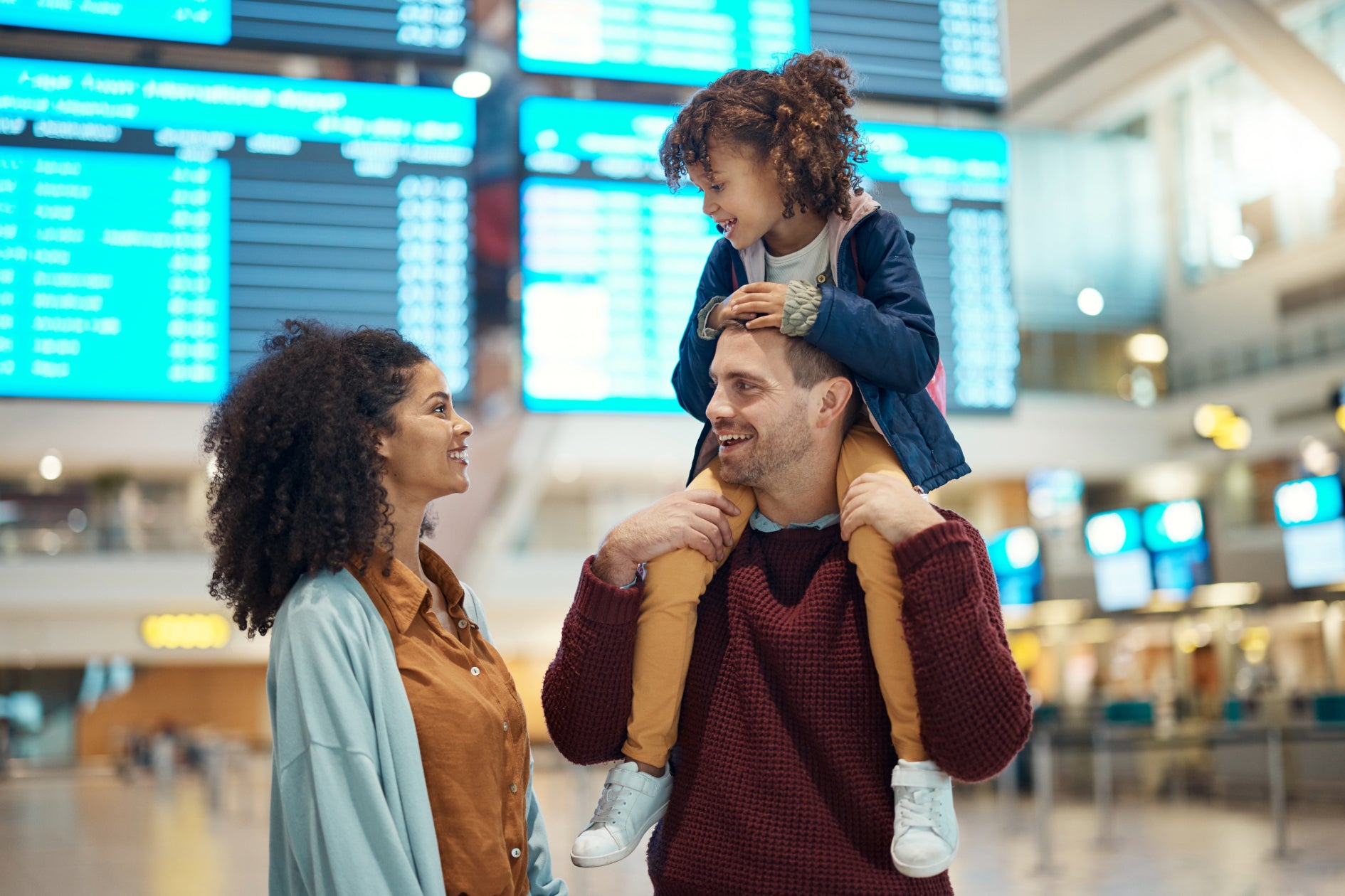 woman and man in an airport with a young girl sitting on mans shoulders